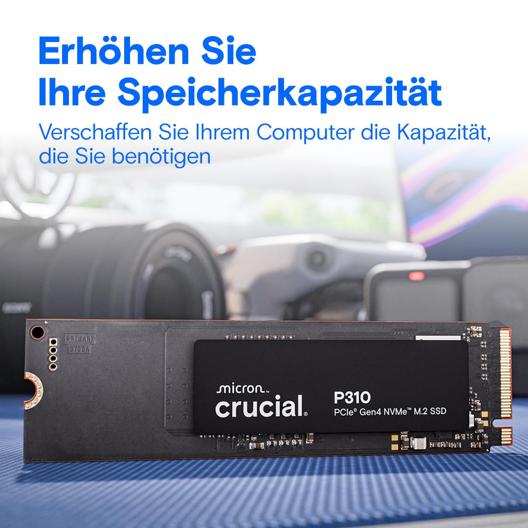 Un SSD M.2 Crucial P310 nero su una superficie blu, con obiettivi di fotocamera sfocati sullo sfondo.