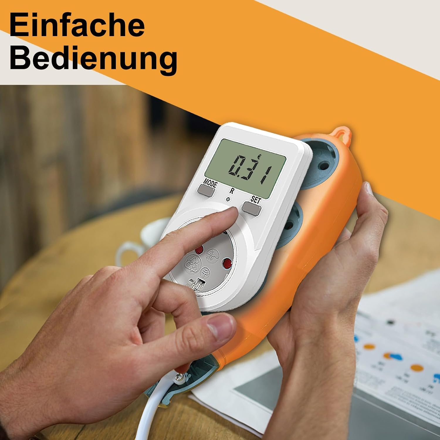 Person bedient ein weiß-orangefarbenes Energiemessgerät mit digitalem Display an einer Steckerleiste.