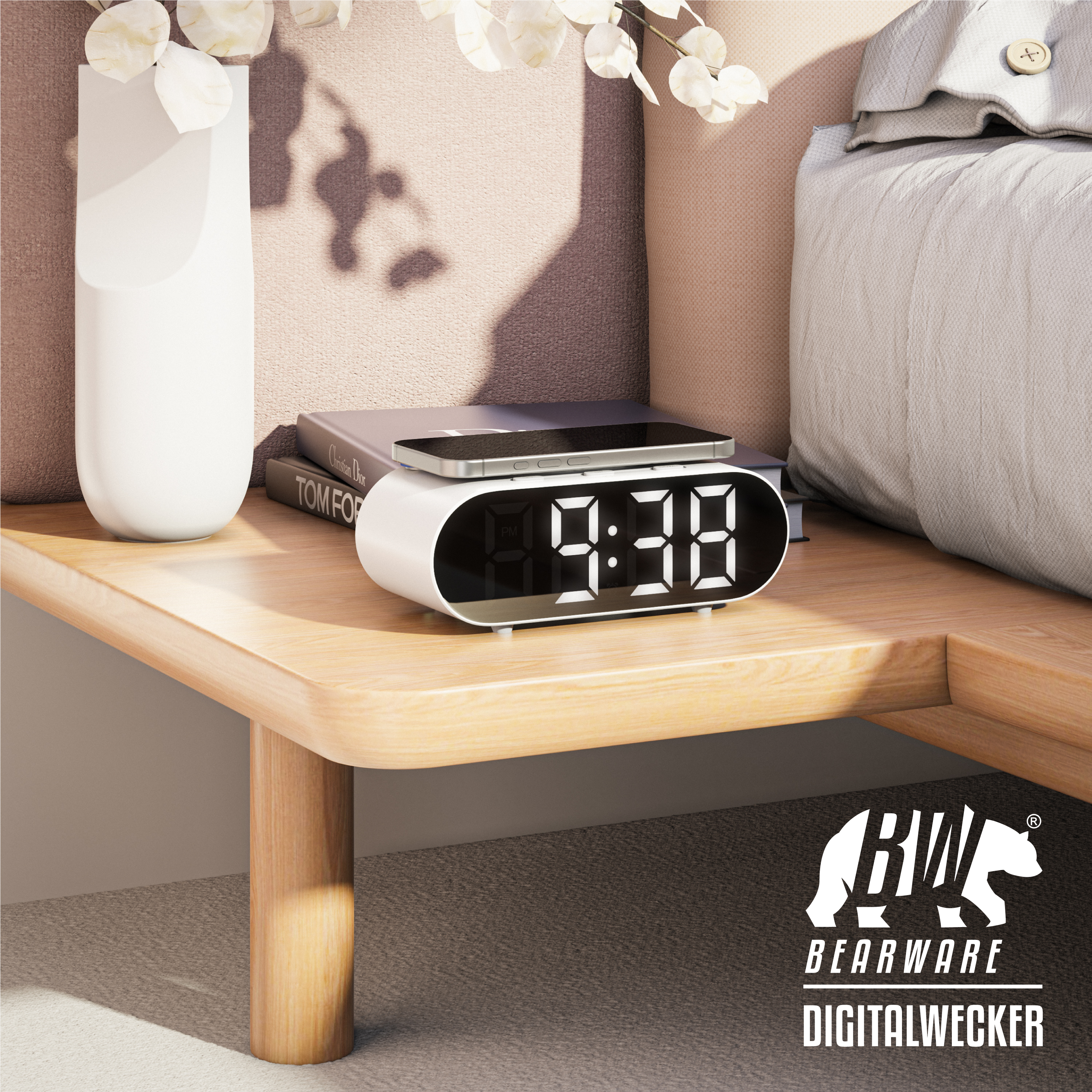 Eine weiße Digitaluhr mit Telefon liegt auf einem Nachttisch aus Holz neben Bett und Büchern.