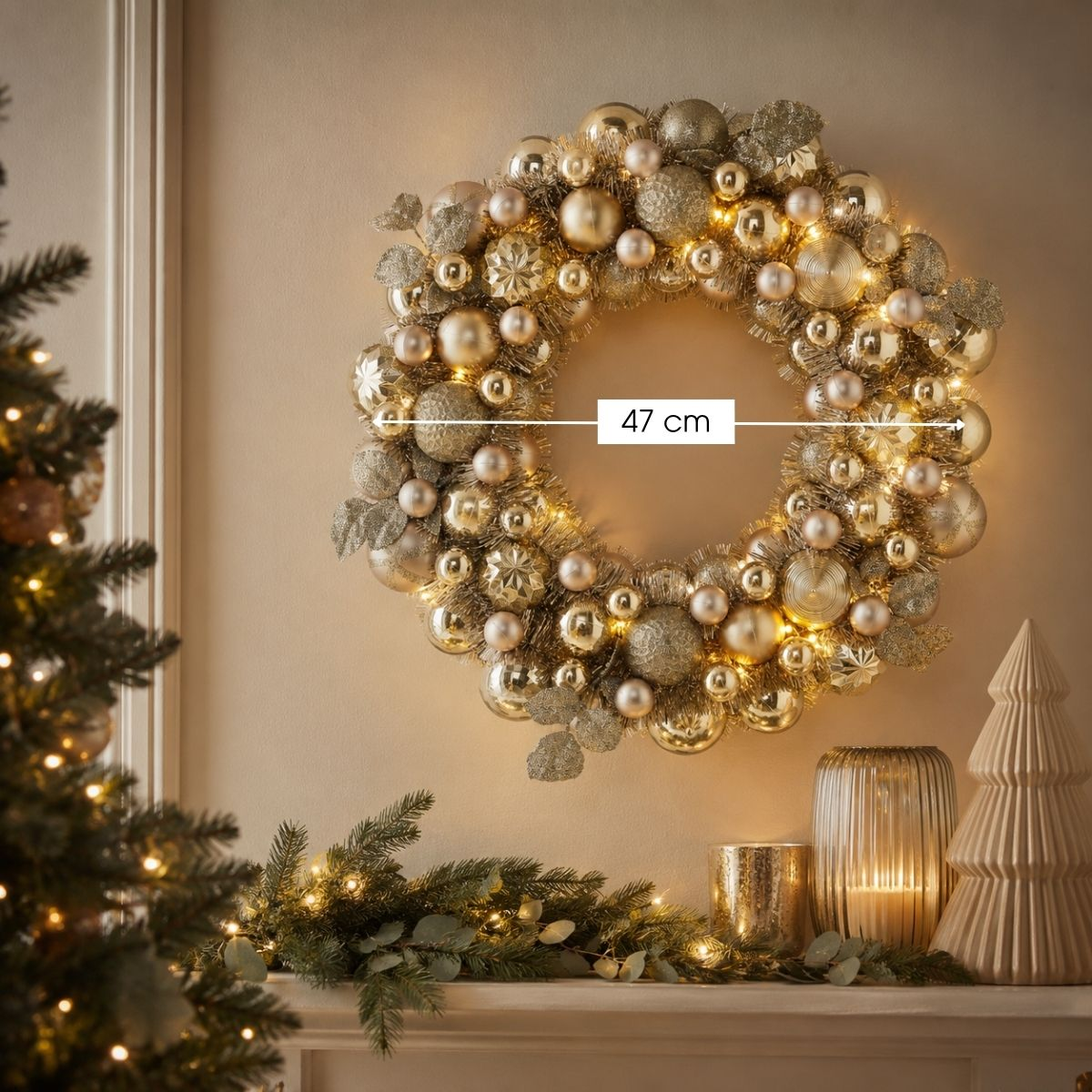 A lit gold Christmas wreath, 47 cm wide, hanging on a wall above a decorated mantelpiece.