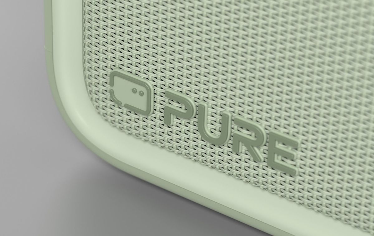 Primer plano de una rejilla de altavoz verde claro con la palabra PURE en relieve y un pequeño icono.