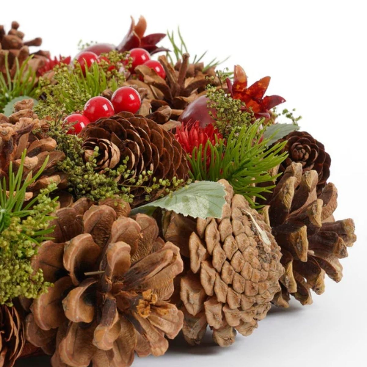 Christmas wreath featuring pinecones, red berries, and green foliage against a white background.
