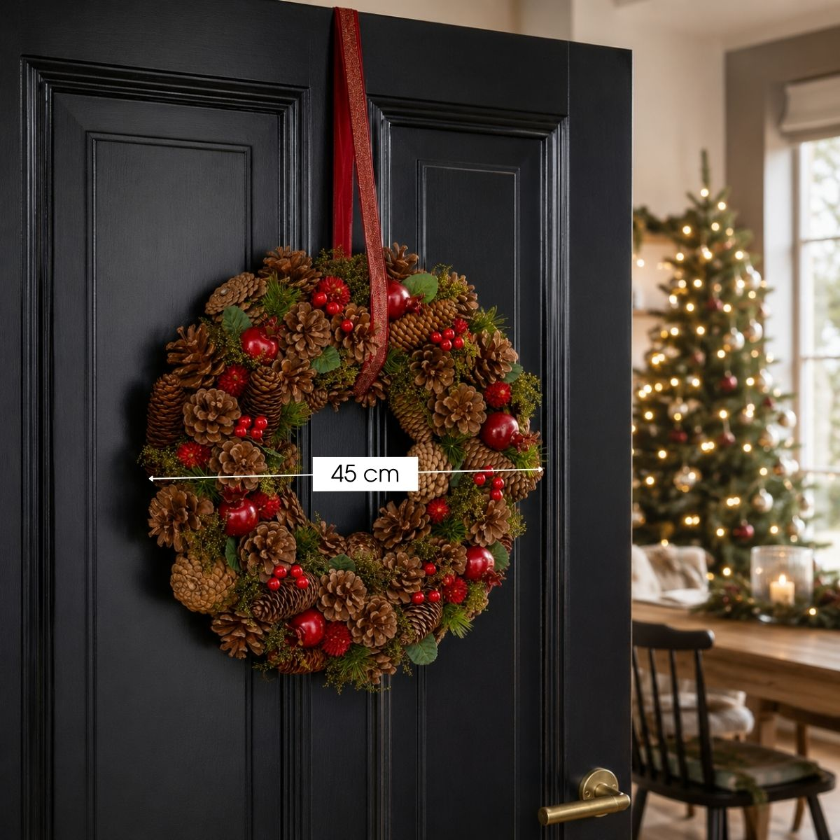 A 45 cm Christmas wreath made of pinecones and red berries hangs on a black door.
