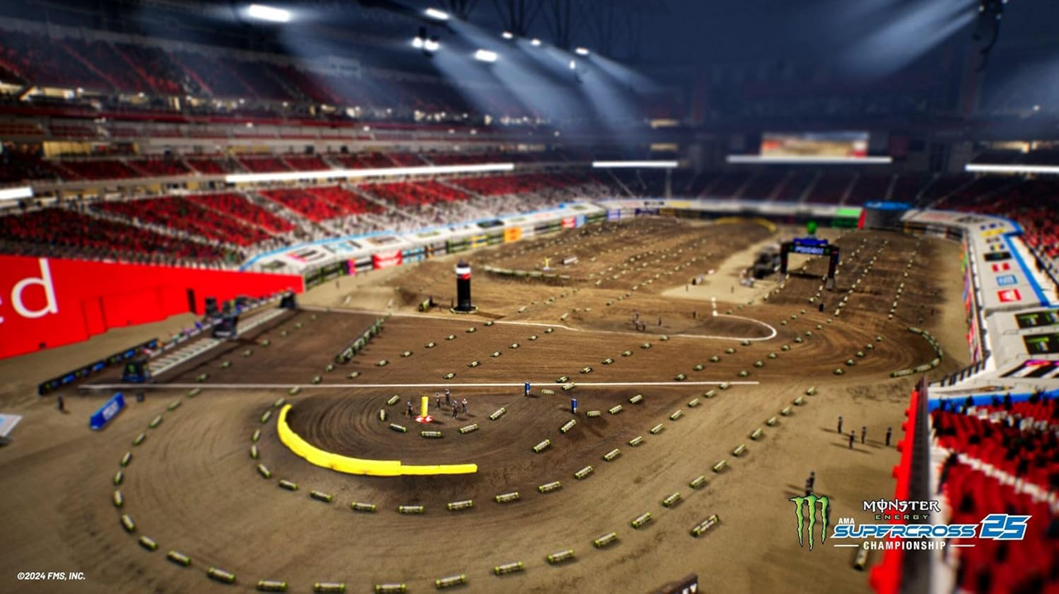 Vista elevada de una pista de supercross de tierra dentro de un estadio iluminado con asientos rojos.