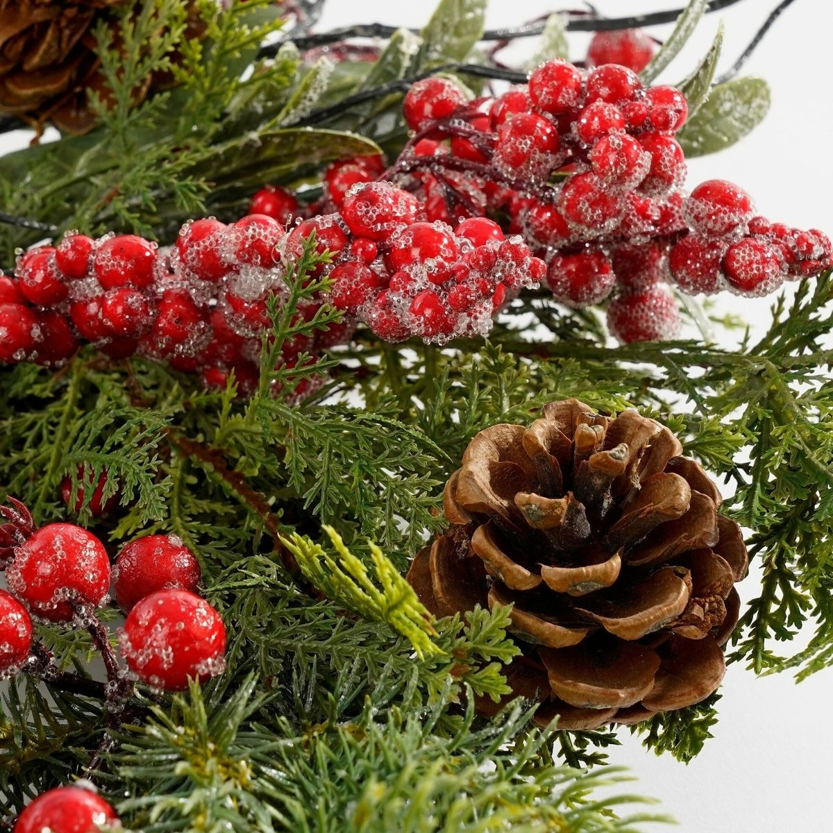 Holiday garland with frosted red berries, pinecones, and green pine branches.