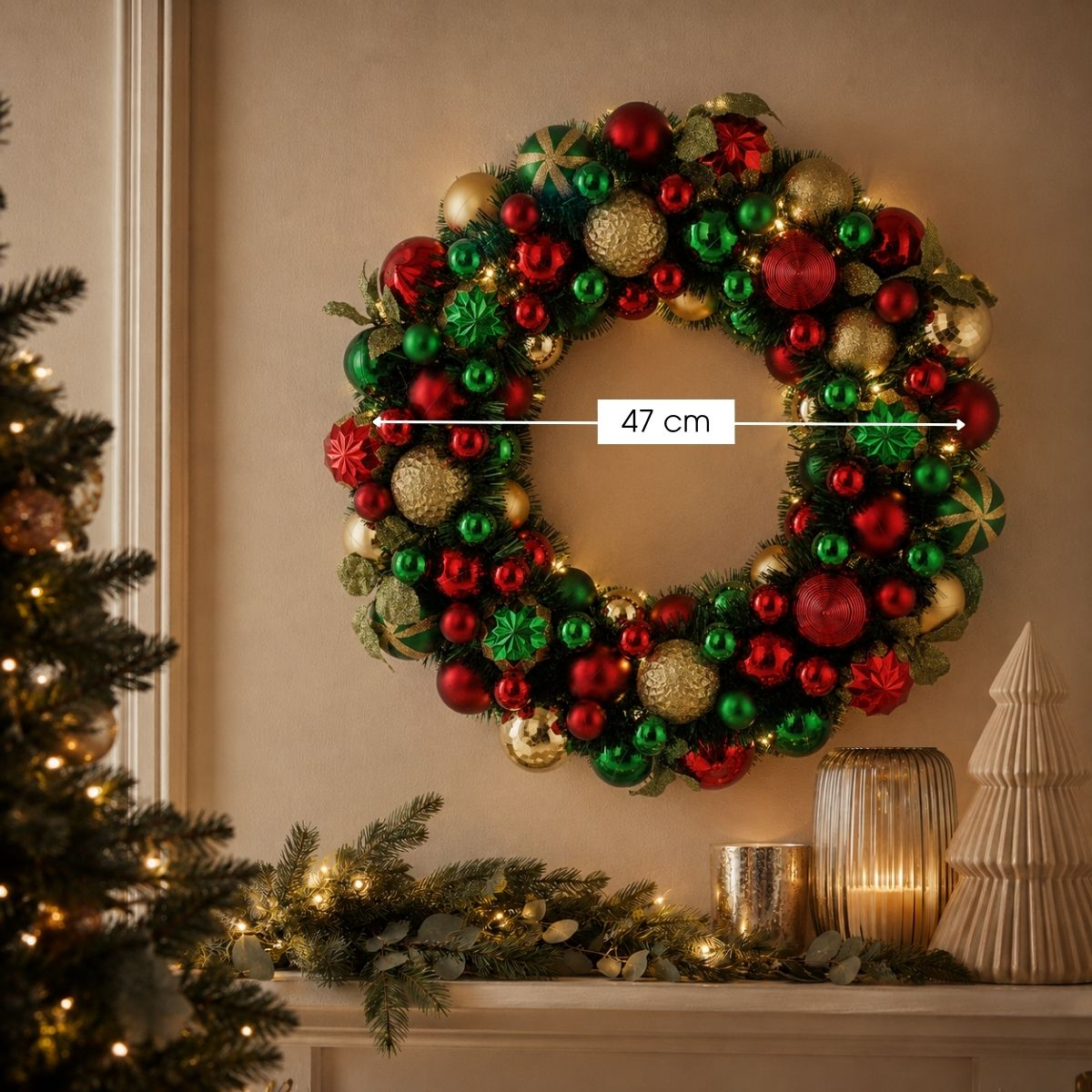 A 47 cm Christmas wreath with red and green ornaments and gold baubles hangs on a wall above a decorated mantel.