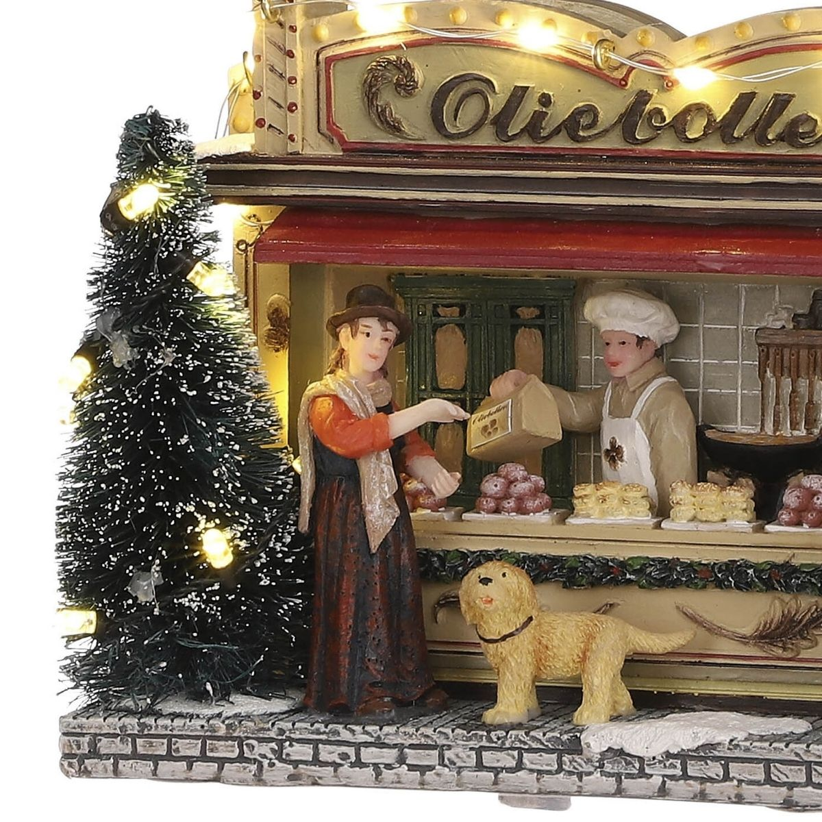 Miniatur-Weihnachtsstand mit Bäcker, Kundin, Hund und geschmücktem Tannenbaum bei Nacht.