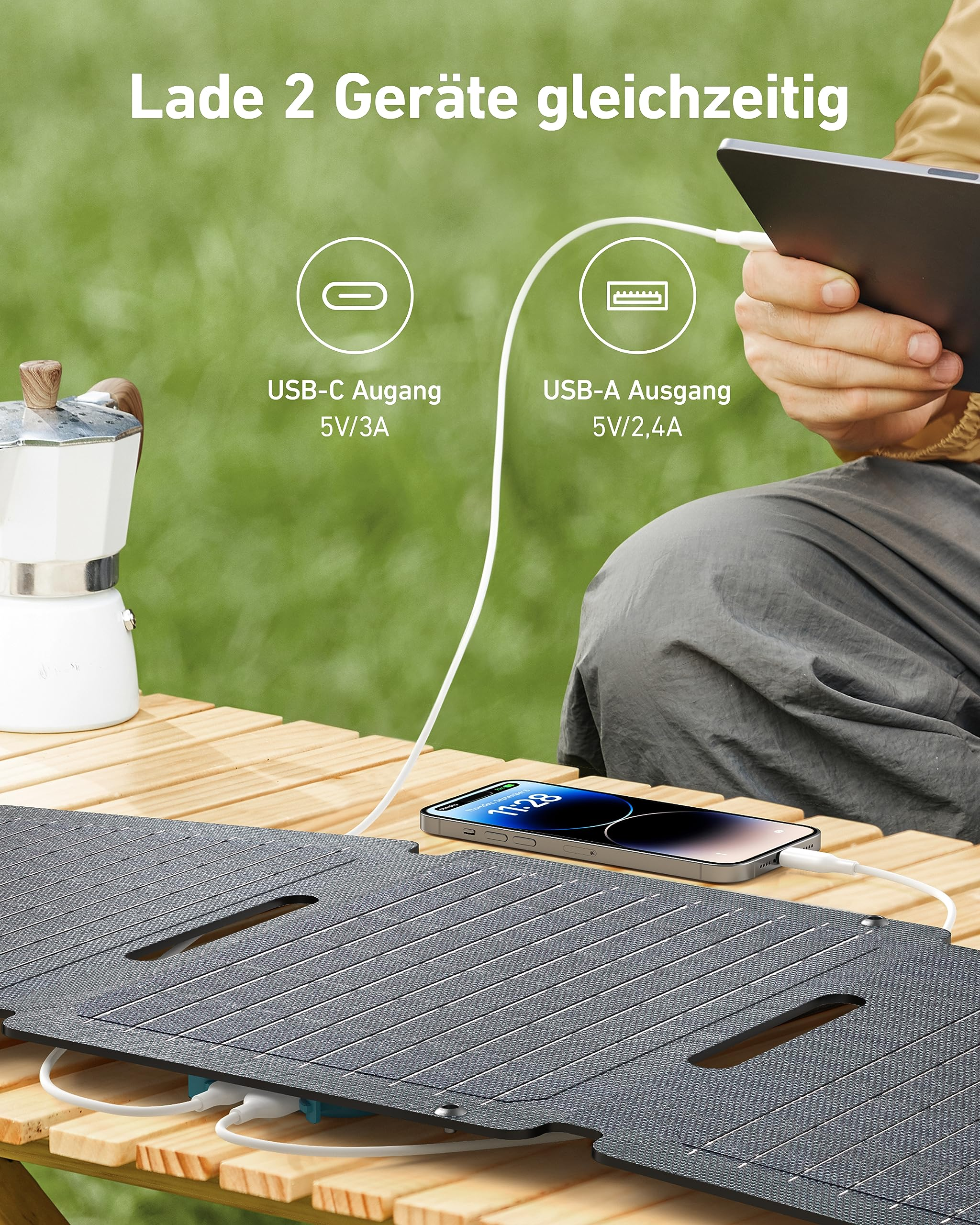 Pannello solare portatile su tavolo di legno che carica contemporaneamente uno smartphone e un tablet.
