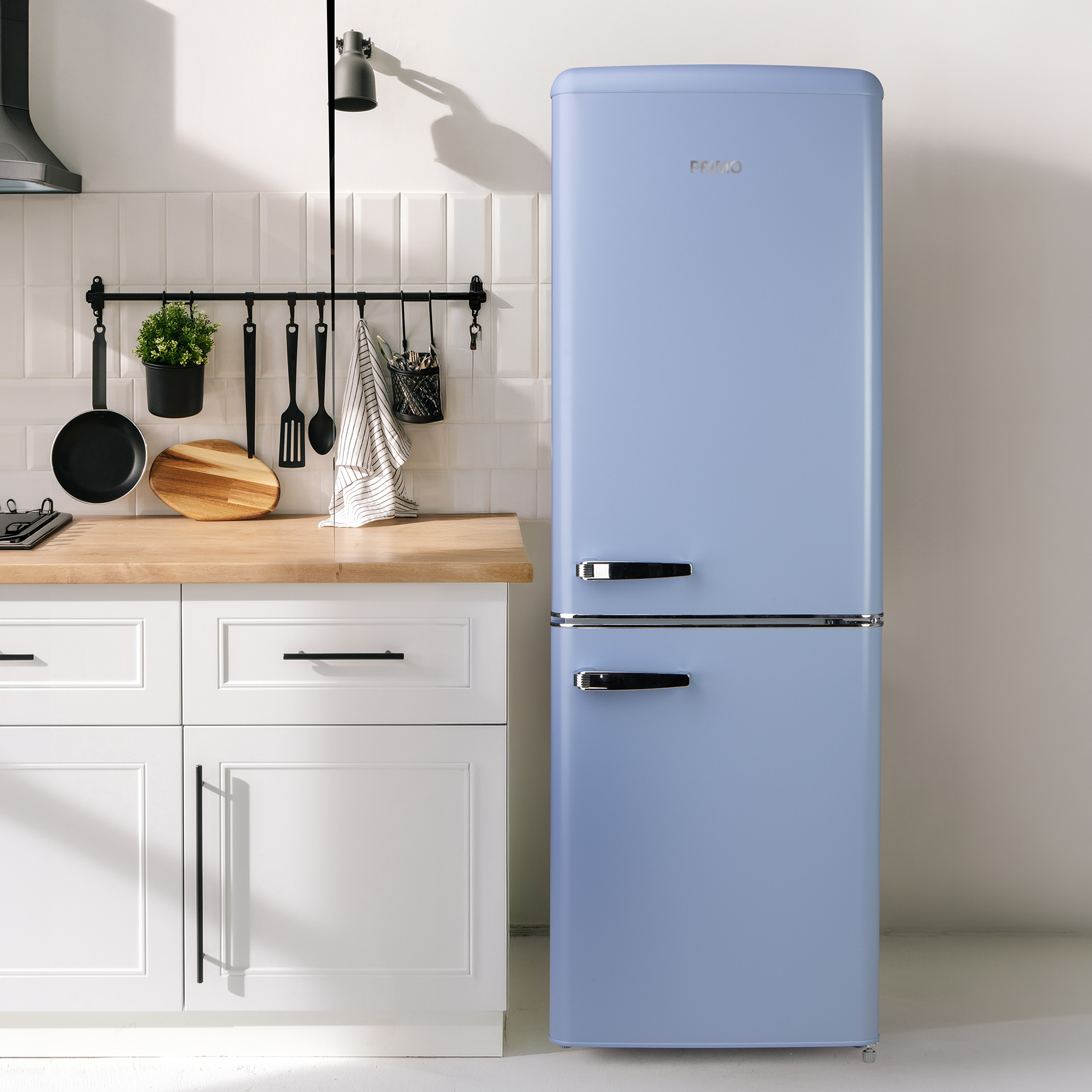 A pastel blue retro refrigerator stands next to white kitchen cabinets with a wooden countertop and hanging utensils.