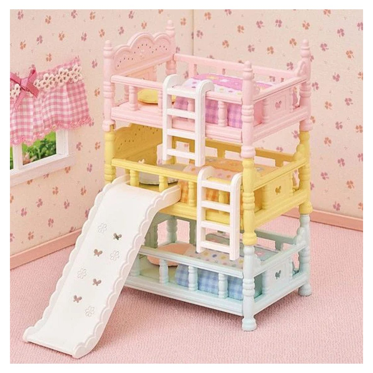 Una litera de juguete de tres pisos en tonos pastel con un tobogán blanco integrado y pequeñas escaleras.
