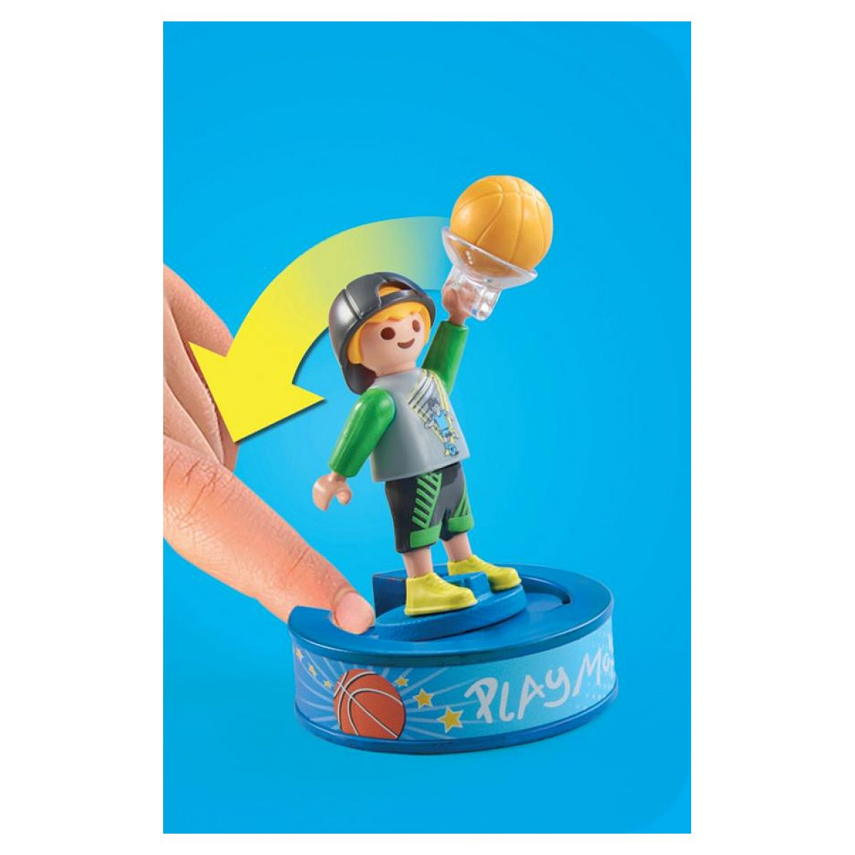 Eine Spielzeugfigur hält einen Basketball hoch, während eine Hand die Basis vor blauem Hintergrund drückt.
