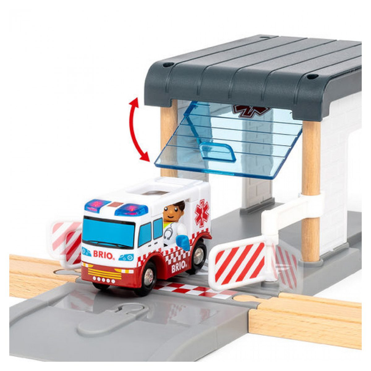 Ein weiß-rotes Brio-Spielzeugkrankenauto fährt aus einer offenen Garage mit Holzsienen.