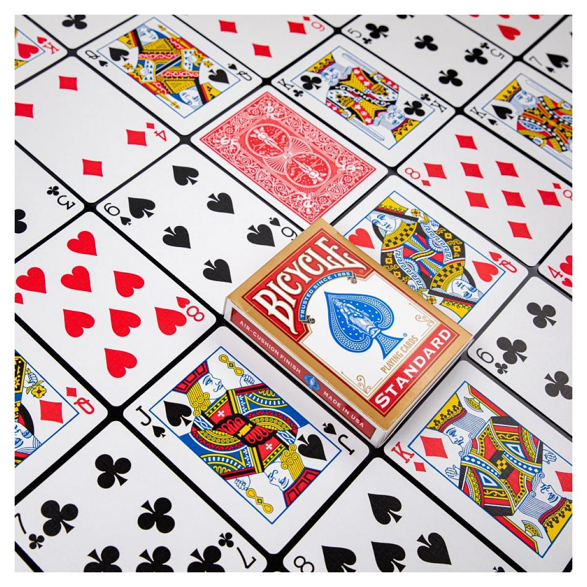 Una baraja de cartas Bicycle rodeada de varias cartas con figuras y números sobre un fondo blanco.