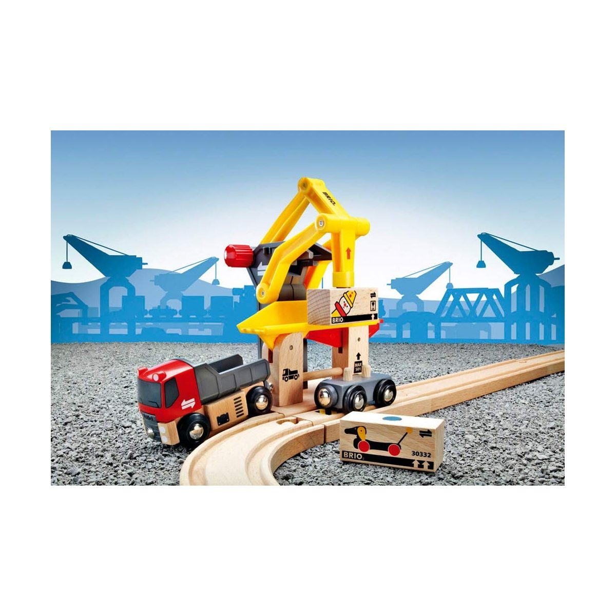 Ein hölzerner Spielzeugkran, ein Lastwagen und Frachtblöcke auf Gleisen vor einem Hafen-Hintergrund.
