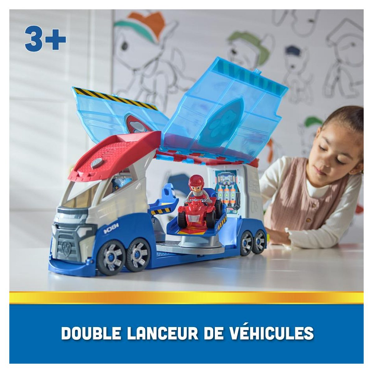 Un niño juega con un gran camión de juguete de Paw Patrol azul y rojo con laterales abatibles y un quad.