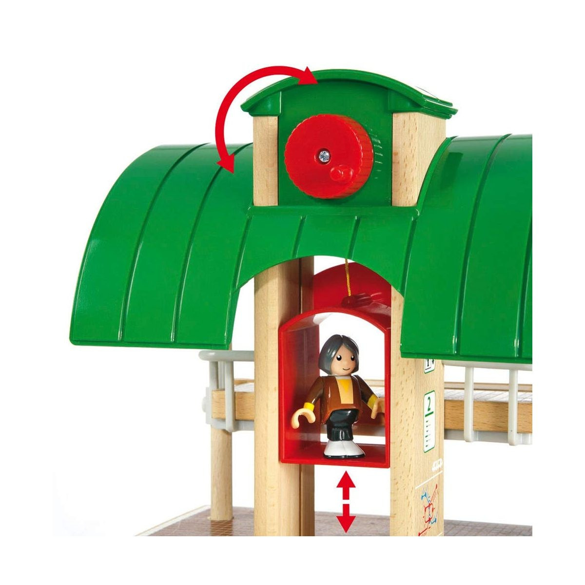 Eine Holzzugstation mit grünem Dach, rotem Rad und einer kleinen Figur in einer roten Fahrstuhlkabine.