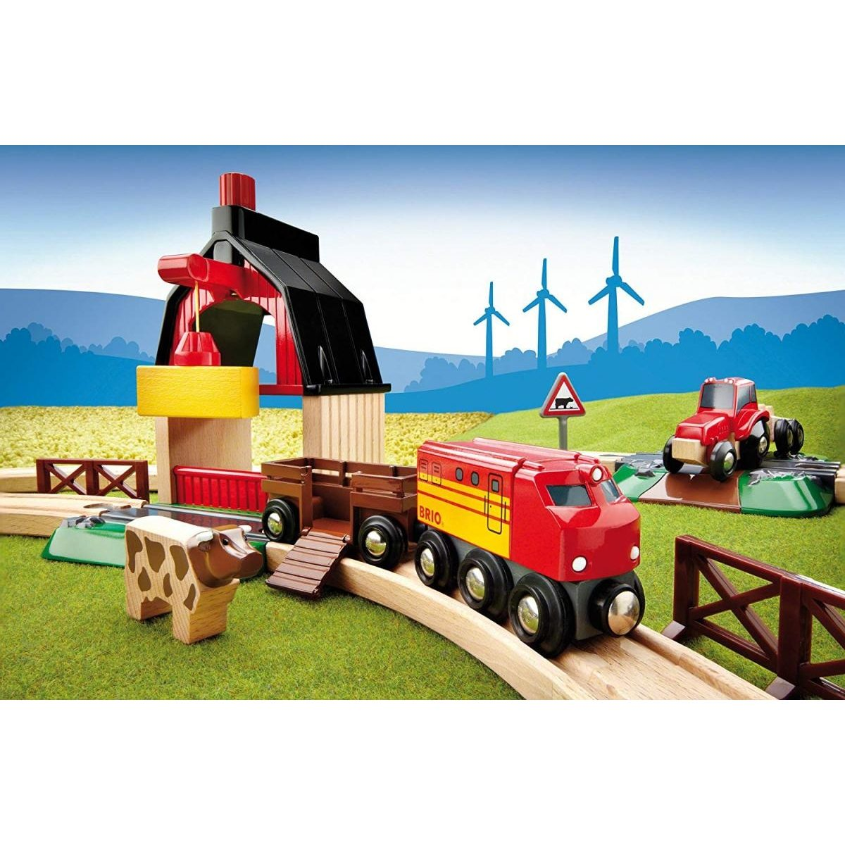 Holzeisenbahn mit rotem Zug, Waggon, Kuh, roter Scheune und Windrädern im Hintergrund auf grünem Feld.