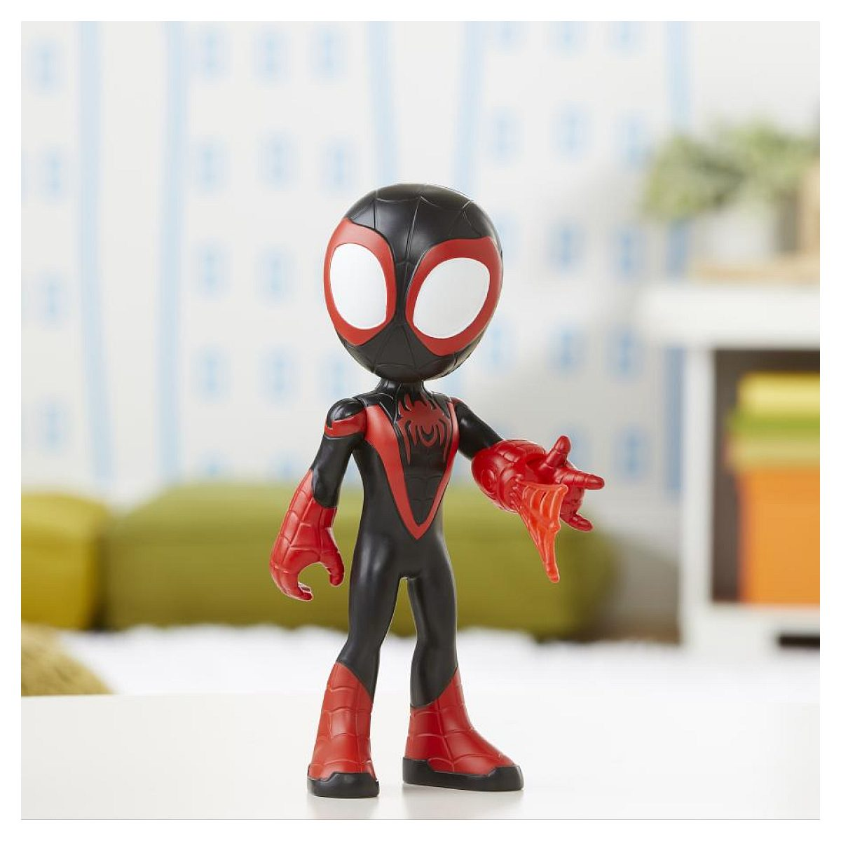 Una figura de acción de Miles Morales en negro y rojo se encuentra en una superficie blanca sobre un fondo borroso.