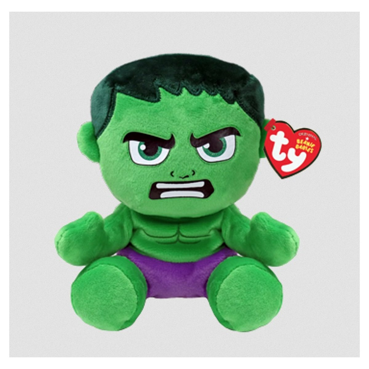Ein grünes Hulk-Plüschtier mit lila Shorts und einem roten, herzförmigen Ty-Etikett am Ohr vor hellem Hintergrund.