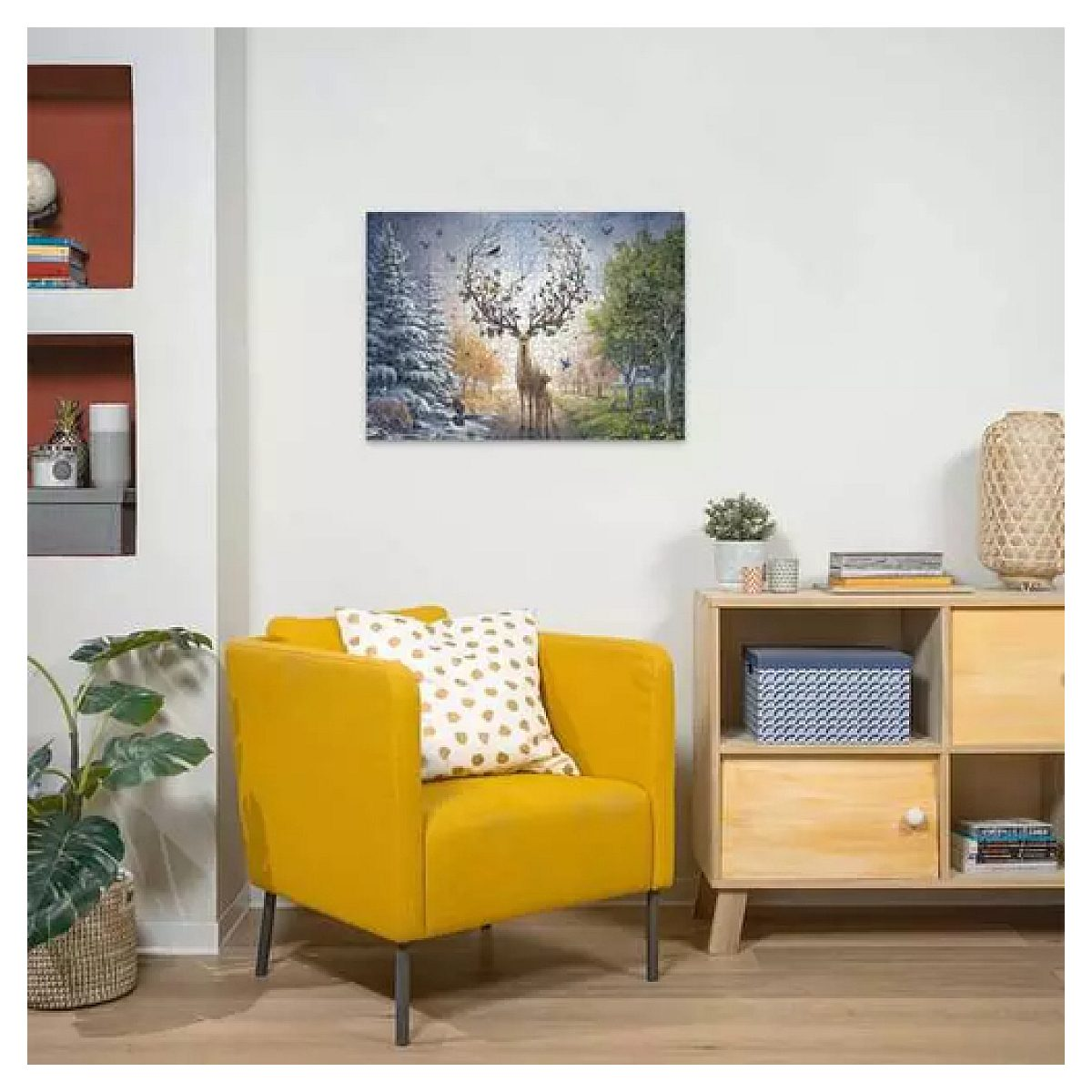 Ein gelber Sessel mit Kissen steht in einem hellen Raum neben einem Natur-Gemälde und Schrank.