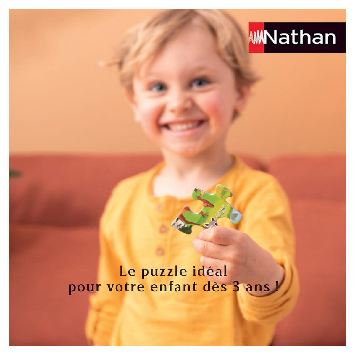 Ein lächelnder Junge in einem gelben Pullover hält ein buntes Puzzleteil in die Kamera.