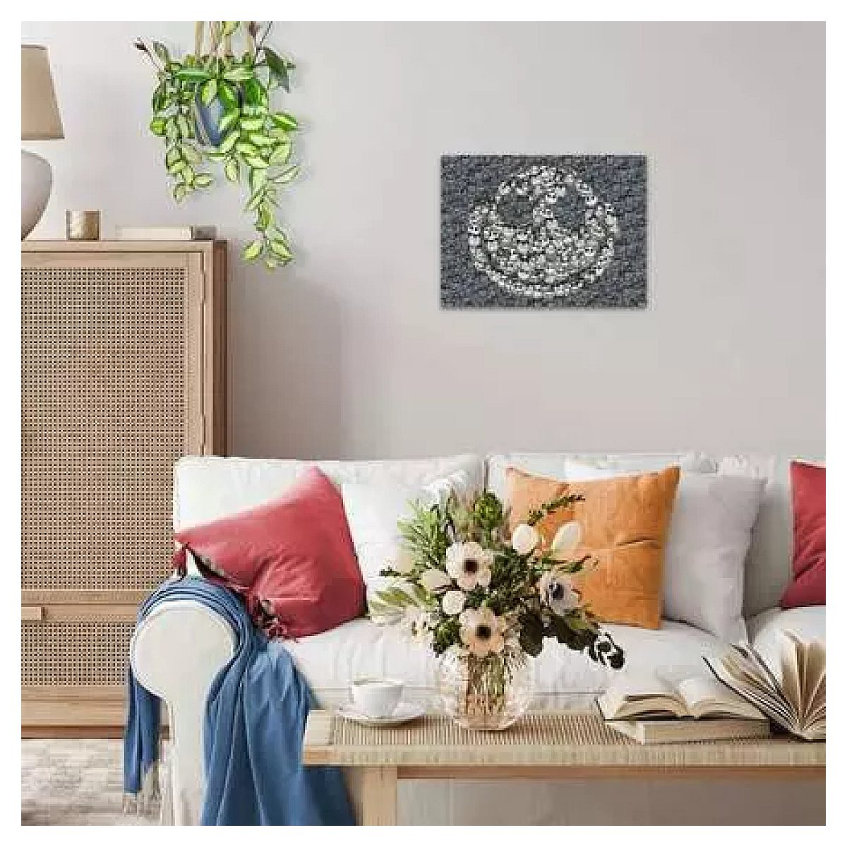 Wohnzimmer mit weißem Sofa, bunten Kissen, Beistelltisch mit Blumen und einem Kunstwerk an der grauen Wand.