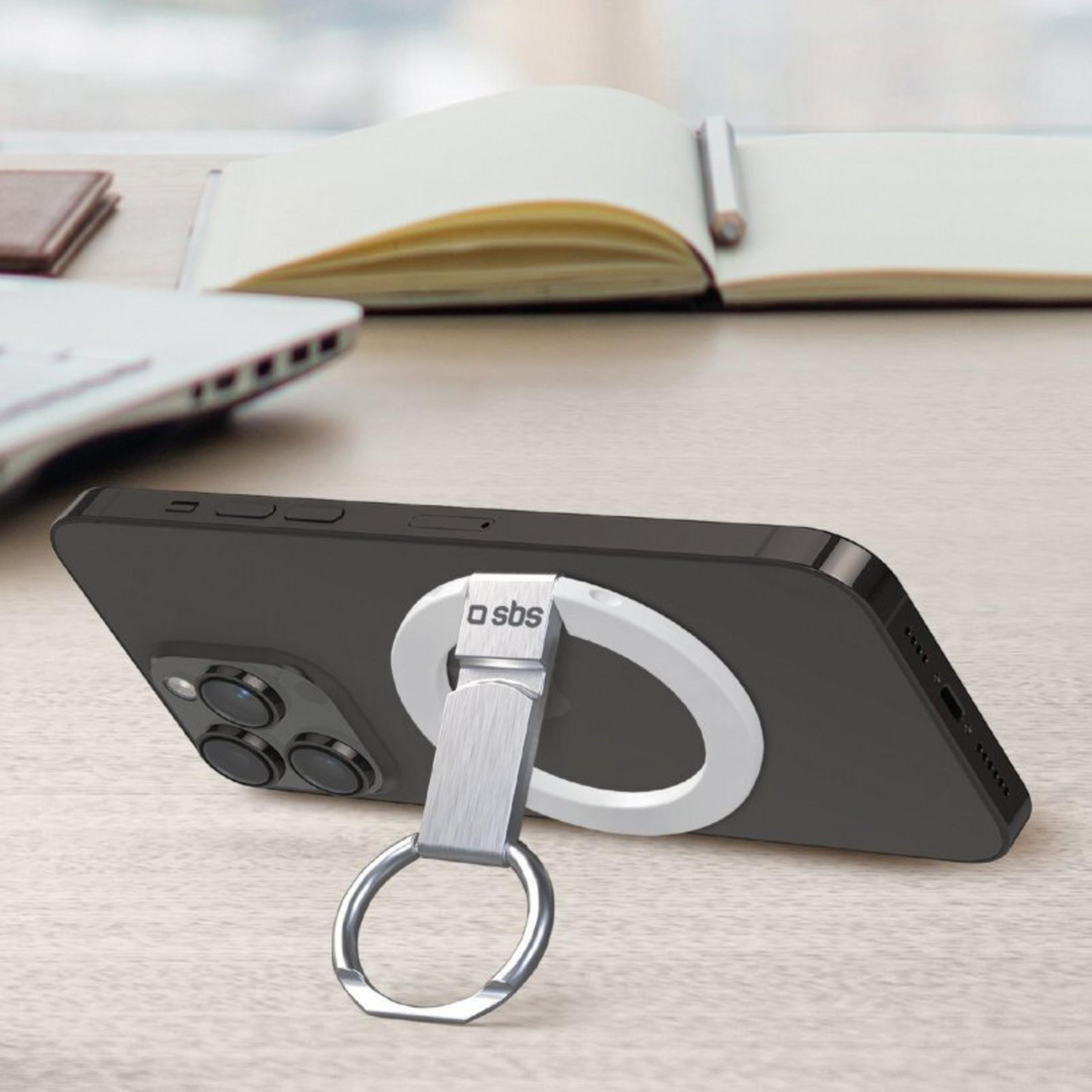Un smartphone negro con un soporte de anillo plateado en un escritorio con un cuaderno.