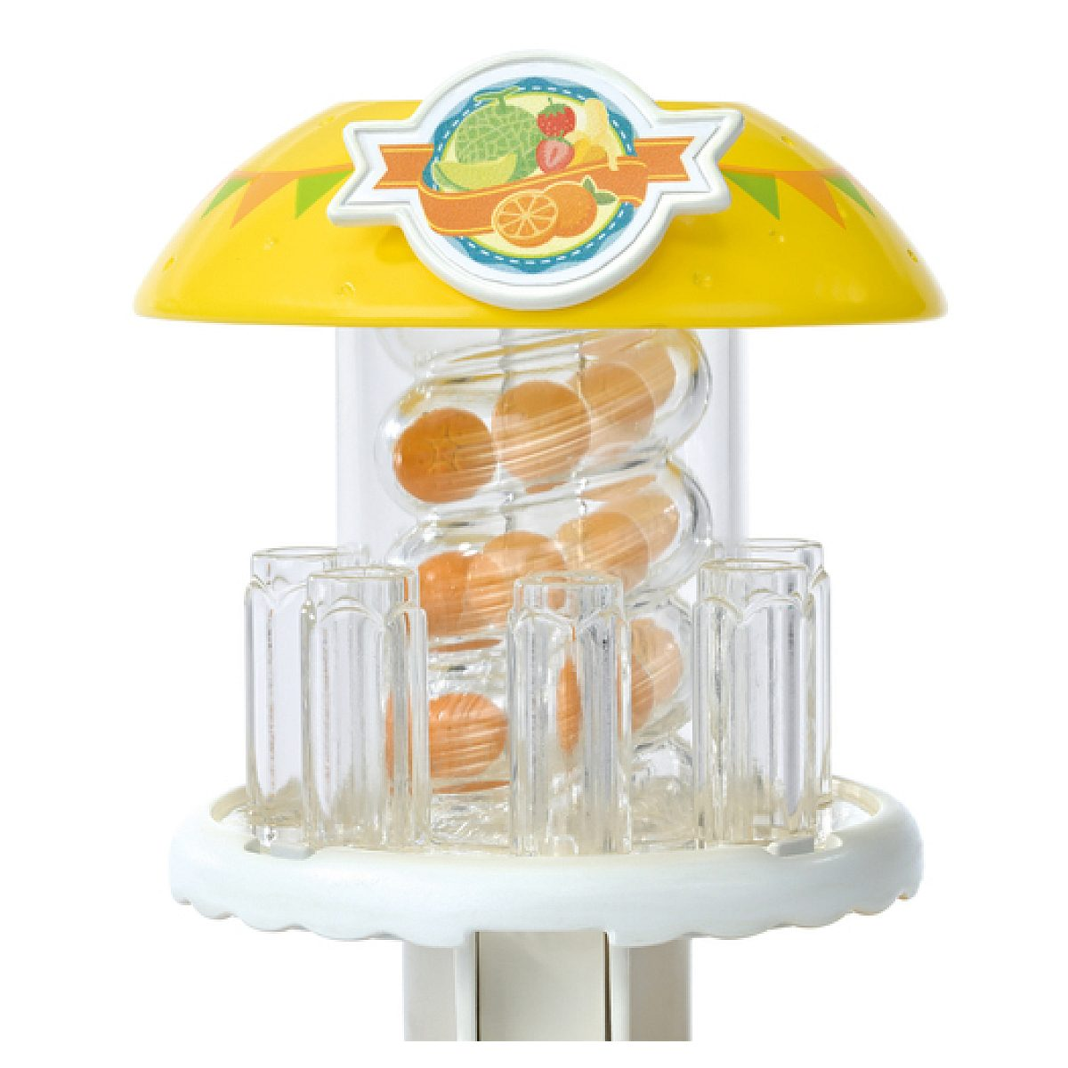 Puesto de frutas de juguete amarillo con tubos transparentes y pequeñas bolas naranjas, rodeado de vasos transparentes.