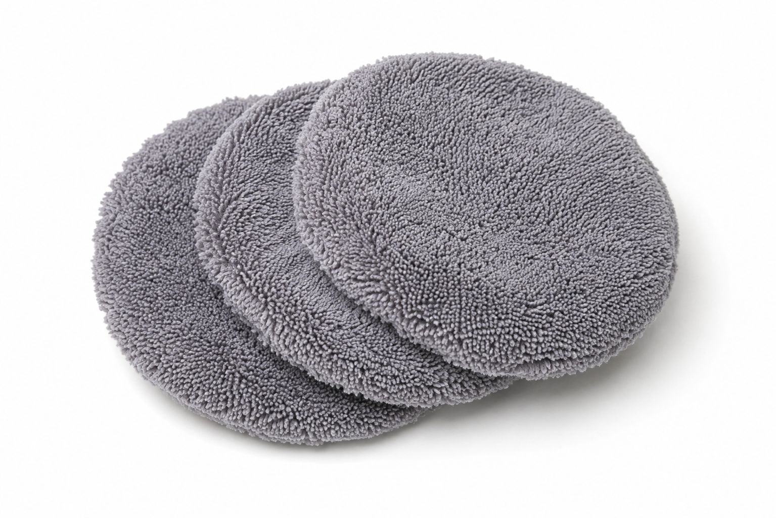 Beyaz bir arka plan üzerinde üst üste binen üç yuvarlak, gri mikrofiber ped.