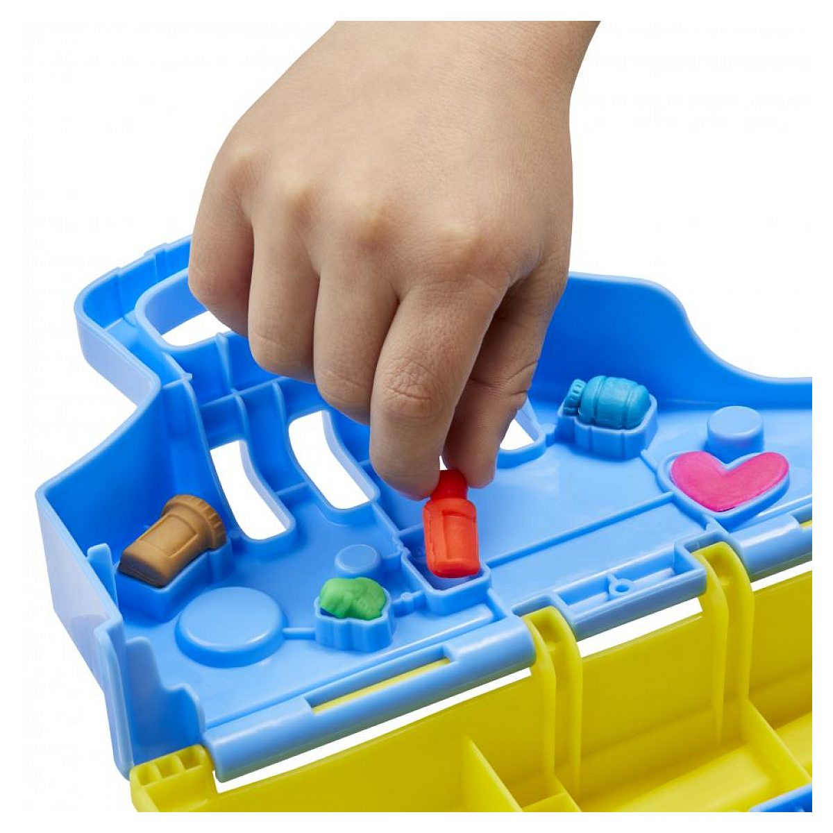 La mano de un niño coloca una pieza de plástico roja en una caja de clasificación azul y amarilla.