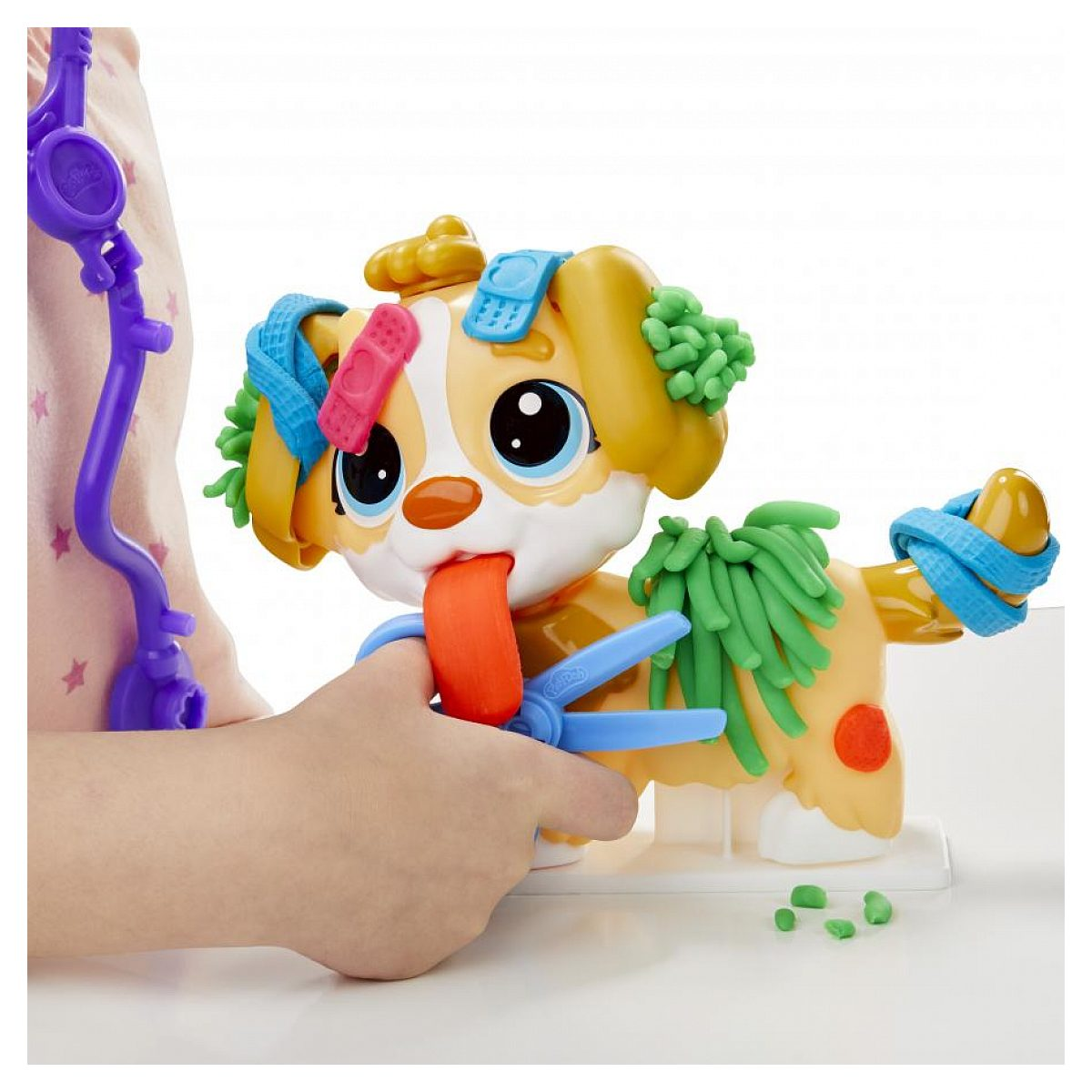 Un niño juega con un perro de juguete de plástico decorado con parches de plastilina coloridos y tiritas.