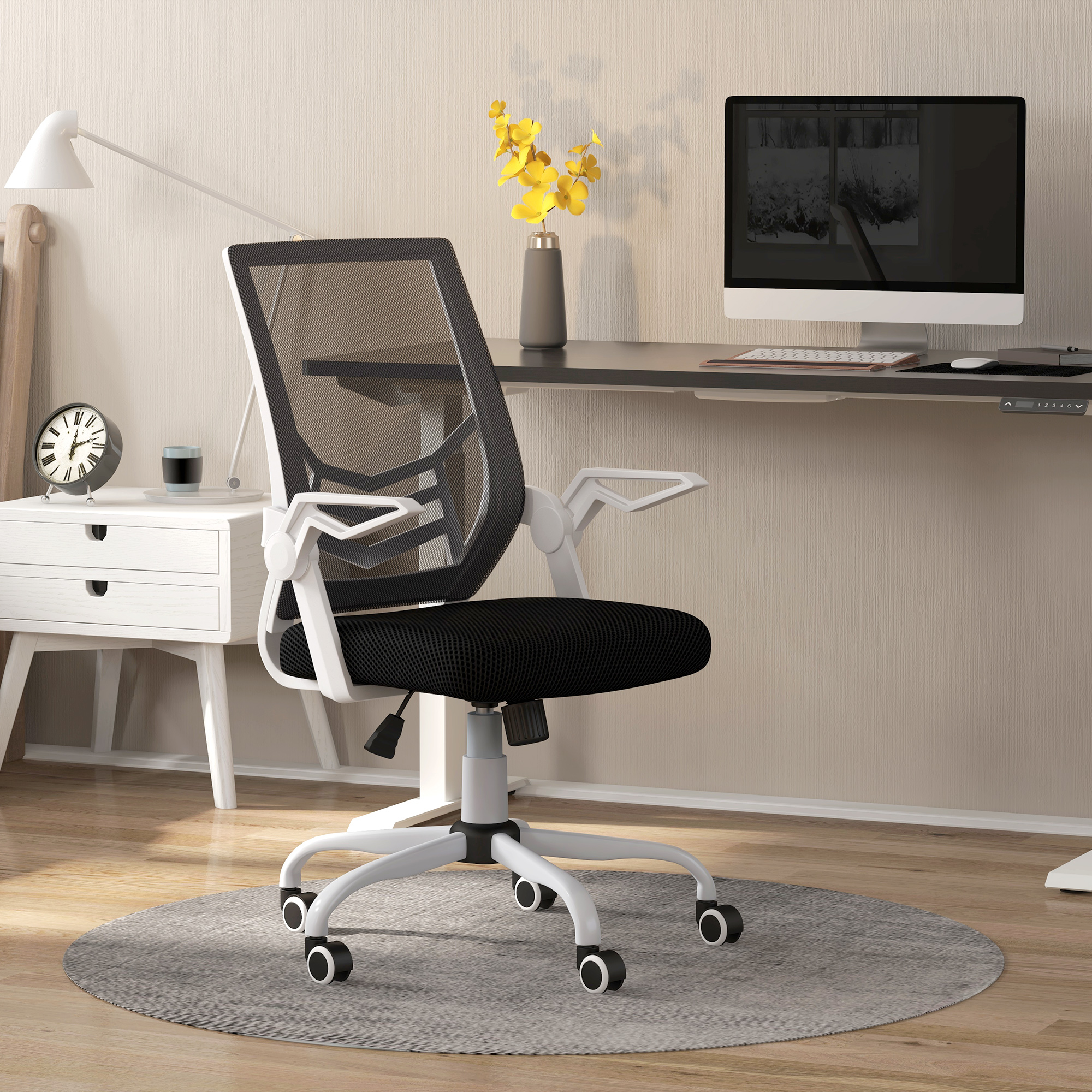 Una sedia da ufficcio in bianco e nero si trova in un home office con scrivania e computer.