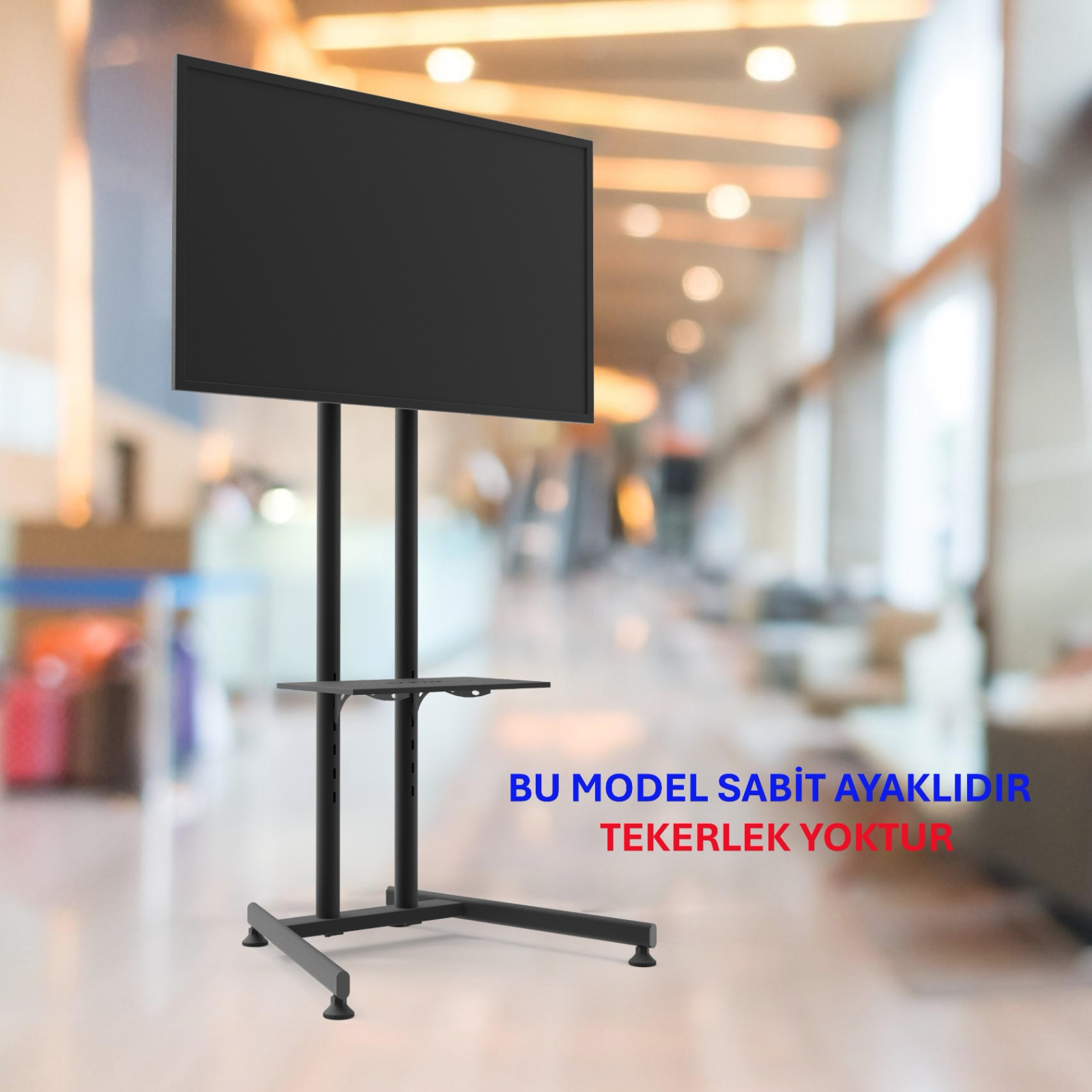 Aydınlık bir koridorda sabit ayaklı büyük bir siyah ekran.