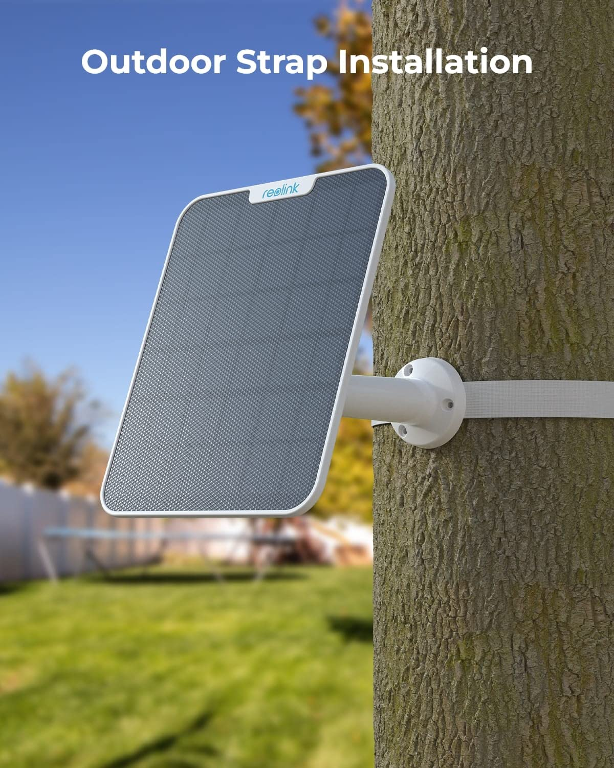 Un pannello solare fissato al tronco di un albero all'aperto, con cielo azzurro e prato sullo sfondo.