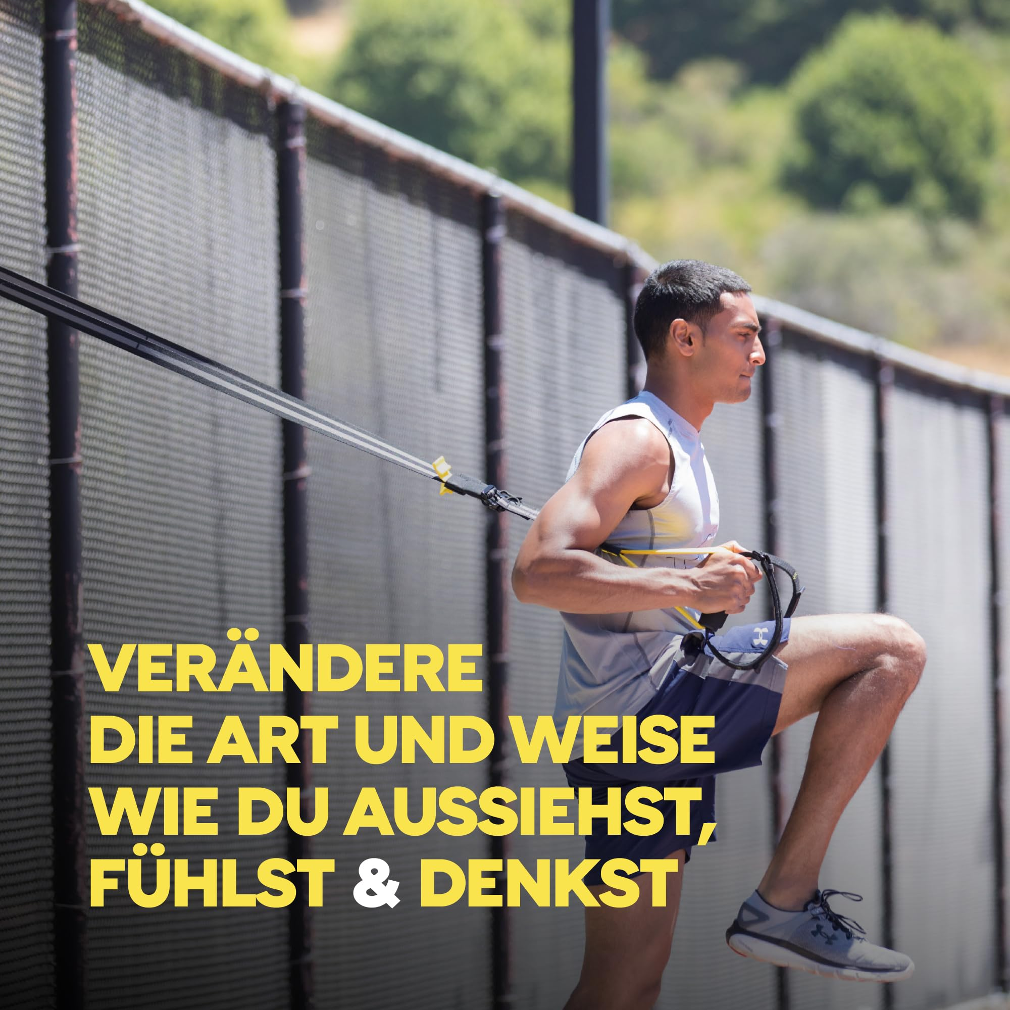 Ein Mann trainiert draußen mit TRX-Bändern vor einem Zaun.