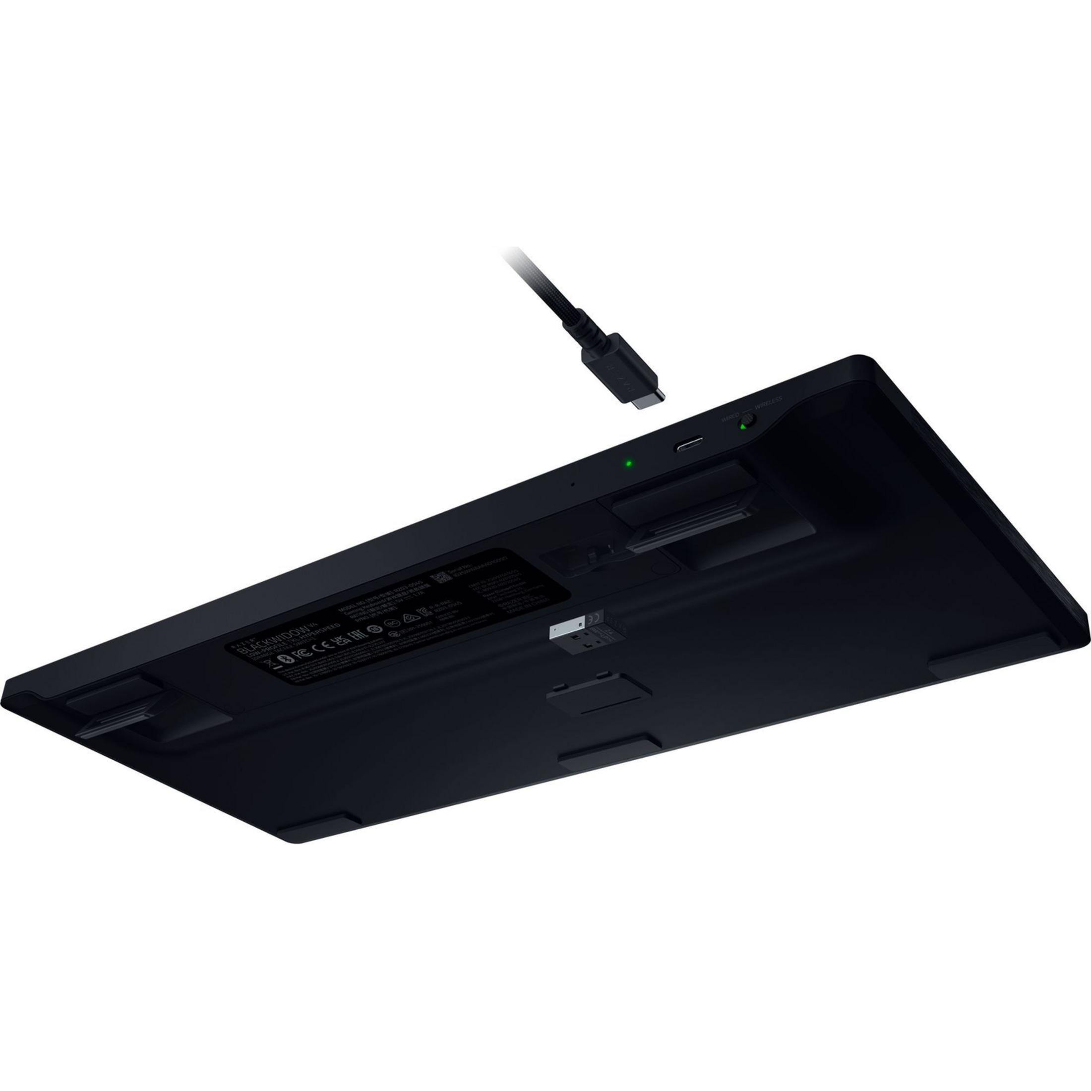 Parte inferiore di una tastiera nera con un cavo USB-C vicino alla porta.