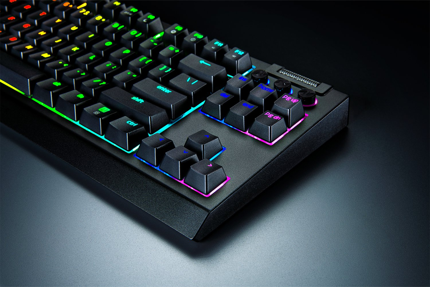 Un teclado de juego negro con retroiluminación RGB vibrante descansa sobre una superficie oscura.