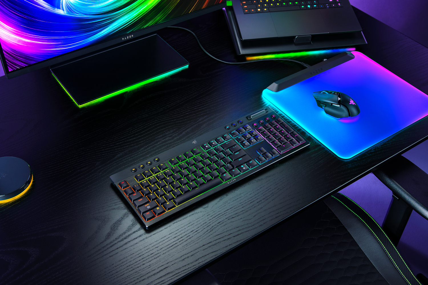 Una scrivania da gioco illuminata con tastiera, mouse, monitor e vivaci luci LED.