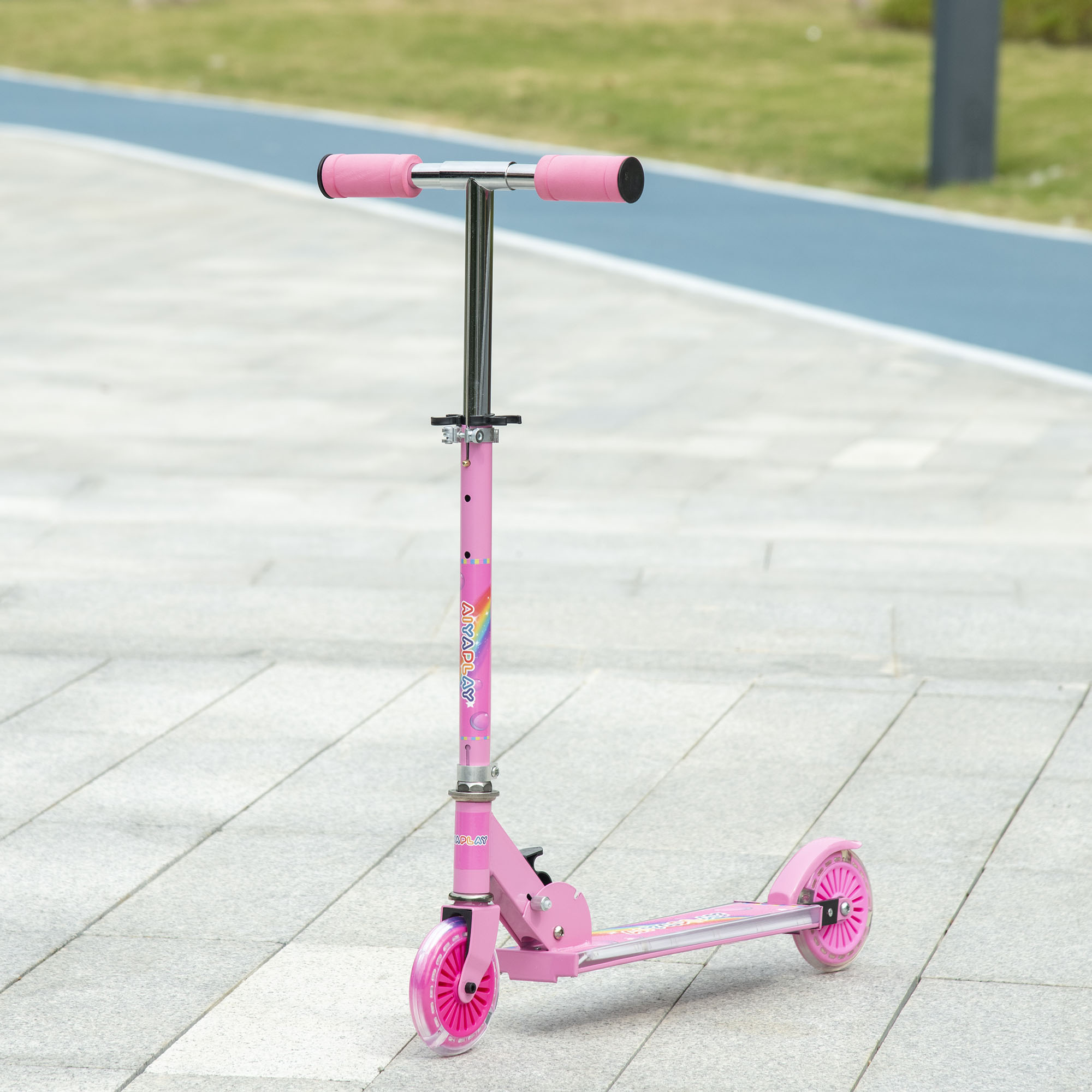 Un monopattino rosa con ruote rosa si trova su un vialetto lastricato all'aperto.