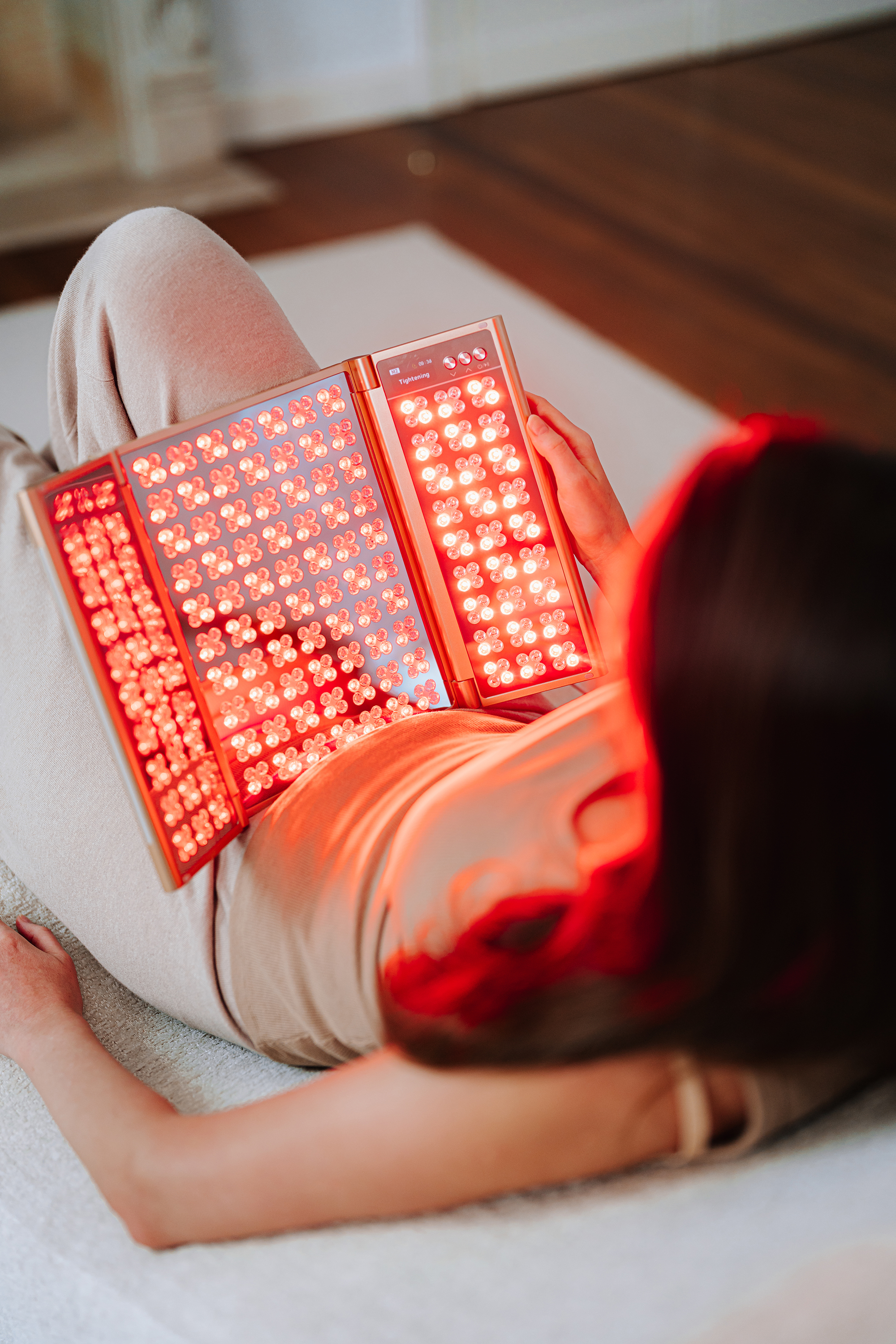 Eine liegende Frau hält ein klappbares Gerät mit vielen roten LED-Lichtern in der Hand.