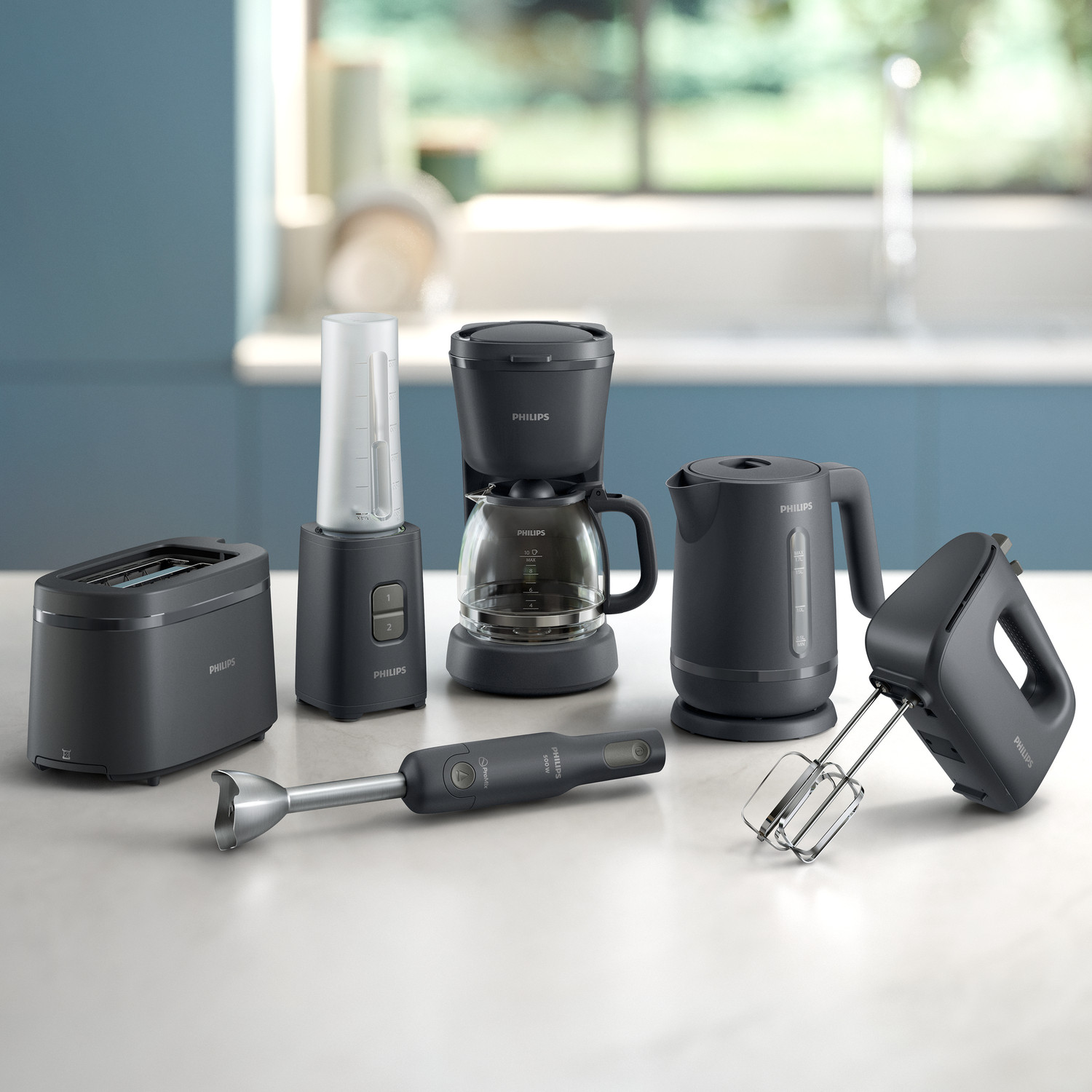 Vari elettrodomestici da cucina neri Philips tra cui tostapane, caffettiera e frullatori su un piano.