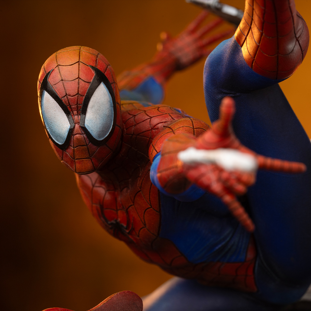 Primo piano di una action figure di Spider-Man rossa e blu in posa dinamica su sfondo caldo.