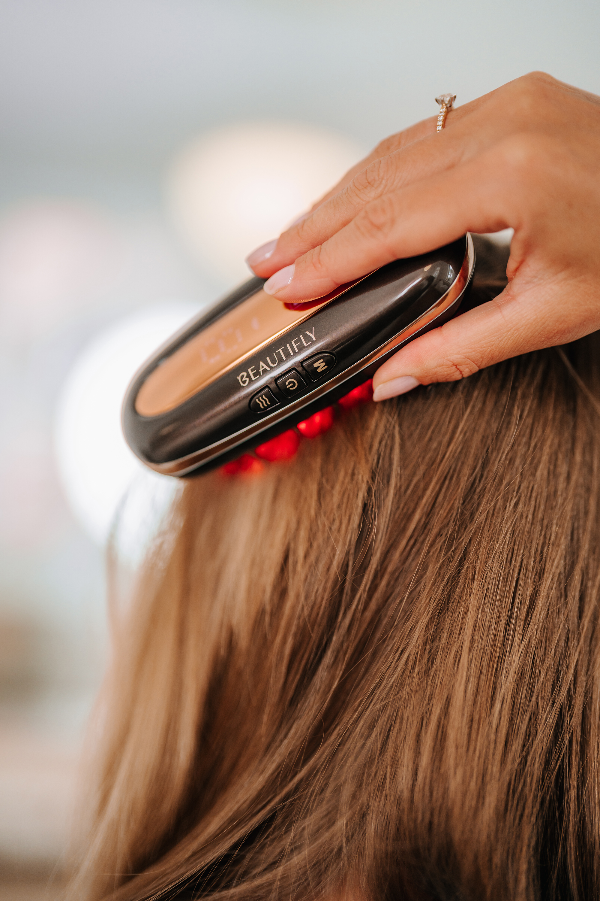 Una mano usa un dispositivo de peinado Beautifly en cabello castaño.