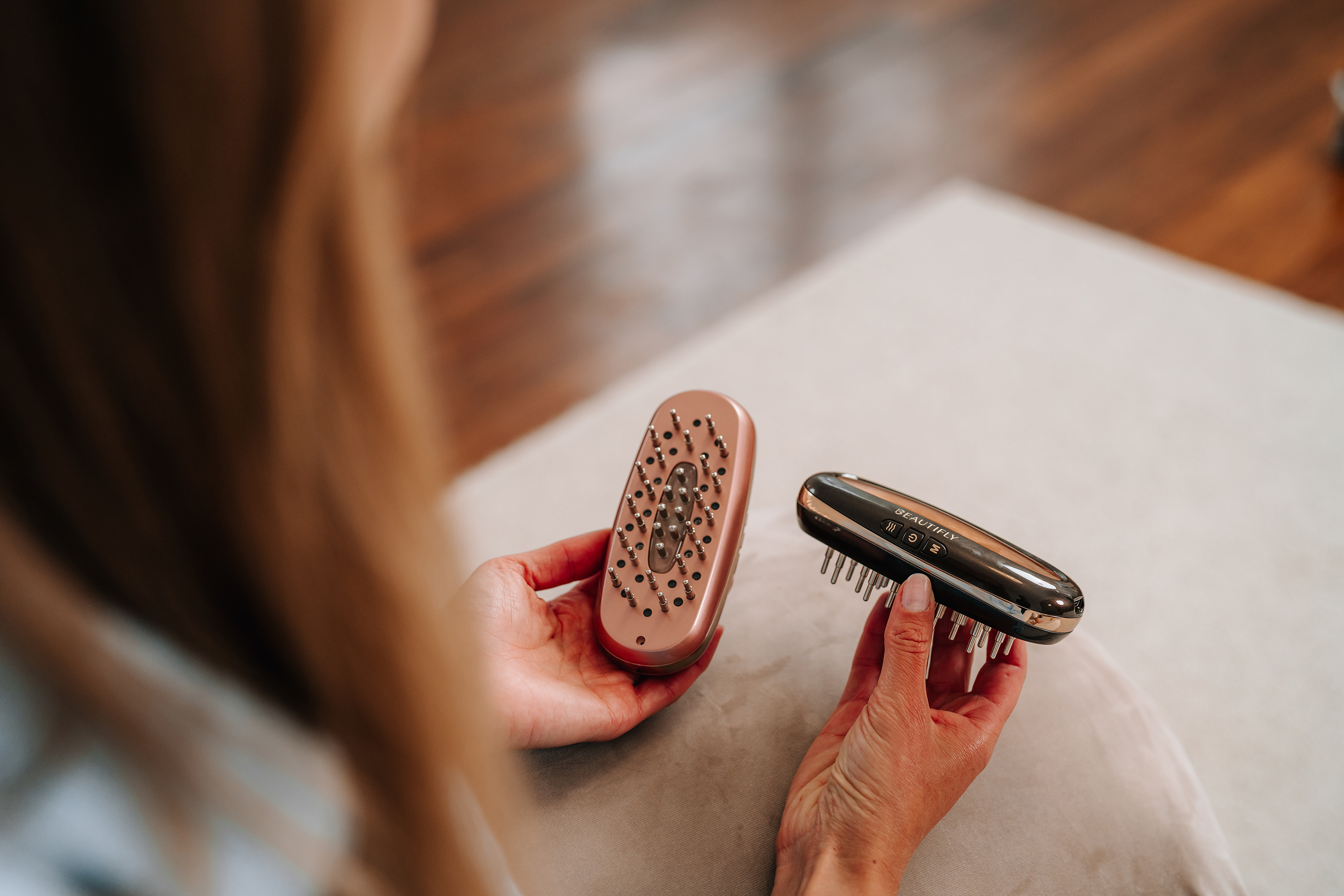 Una persona sostiene dos accesorios de cepillo para el cabello diferentes, uno de oro rosa y otro negro.