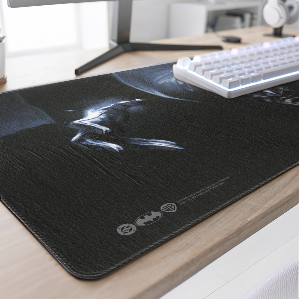 Un tappetino da scrivania nero di Batman con design luminoso, tastiera bianca e supporto per monitor in legno.