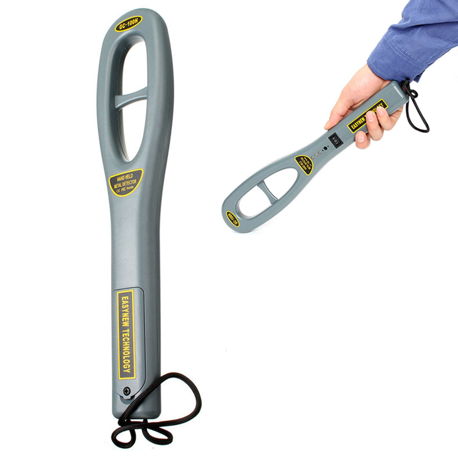 Ein grauer Handmetalldetektor mit gelben Etiketten und einer schwarzen Handschlaufe, teilweise von einer Hand gehalten.