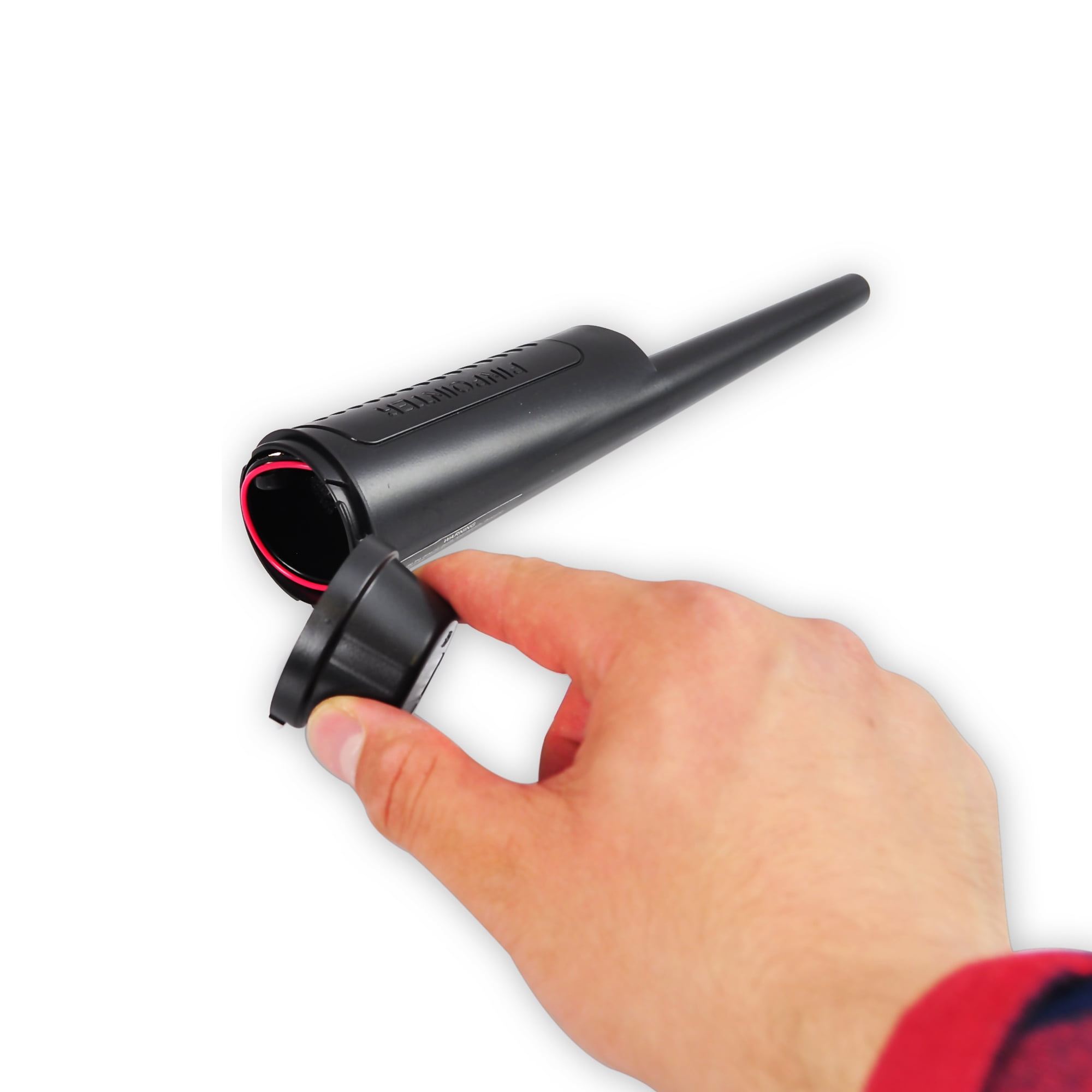 Eine Hand öffnet das Batteriefach eines schwarzen Pinpointers vor weißem Hintergrund.