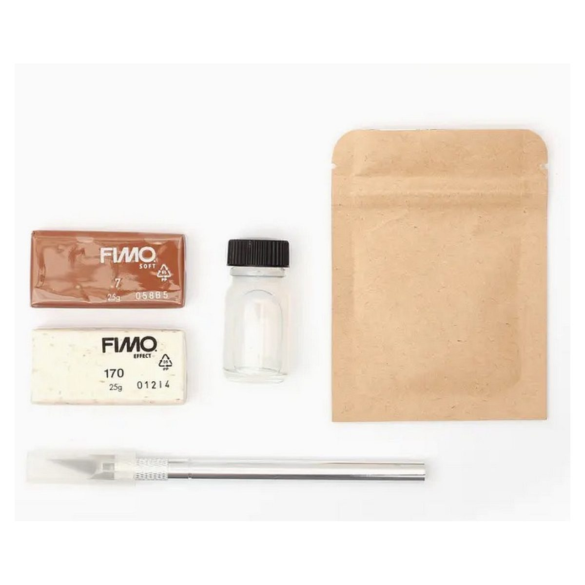 Bastelbedarf umfasst zwei FIMO-Blöcke, eine Glasflasche, einen braunen Papierbeutel und ein Bastelmesser auf weißem Grund.