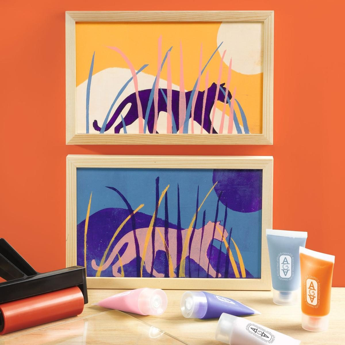 Zwei gerahmte Linolschnitt-Tigerkunstdrucke vor orangefarbenem Hintergrund, mit Farbtuben und einer Walze.