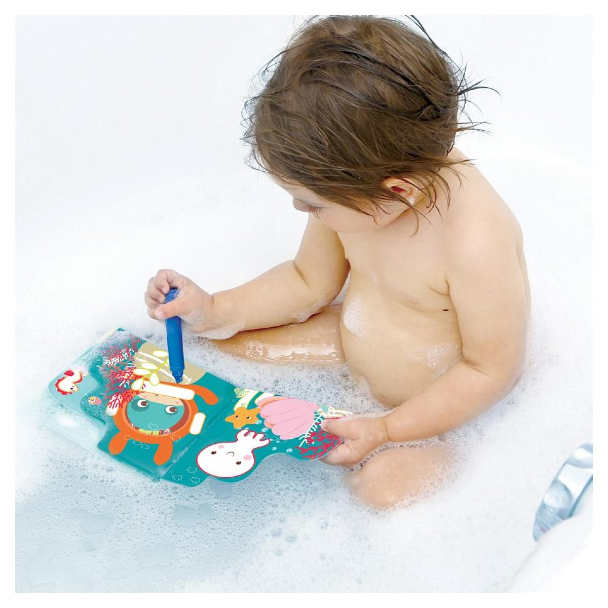 Ein Kleinkind sitzt in einer Badewanne voll Schaum und malt mit einem blauen Stift in einem bunten Buch.